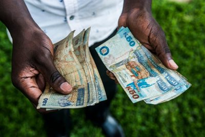 A man holds new bank notes in his left hand and old bank notes in his right hand