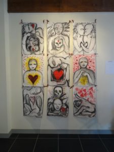 Art by Ruth Hartley: 9 charcoal drawings arranged in a 3 by 3 grid with highlights in reds and yellows. A theme of hearts repeats in each drawing.