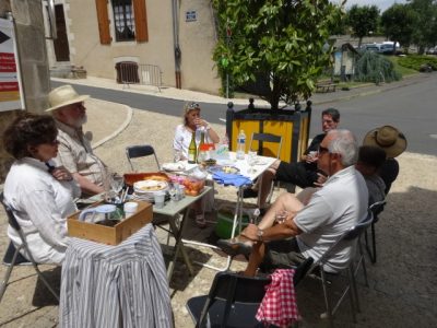 A group of people arounda table eating an informal meal in the street