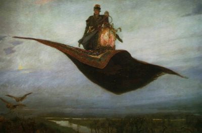A prince in a fur hat and coat stands on his magic carpet next to a glowing lantern. It is twilight as he flies over a river so high that there are birds flying below him