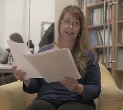 Tanvir Bush smiling as she reads from large-print papers about her book