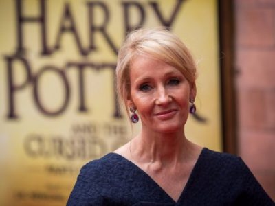 JK Rowling stands in front of a Harry Potter poster