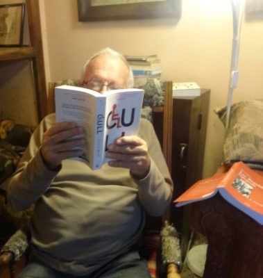 A man in a rocking chair is reading CULL