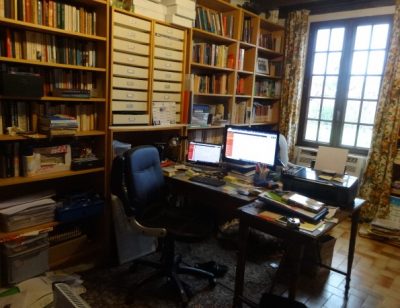 The writer's study lined with bookshelves with a cluttered desk and computer