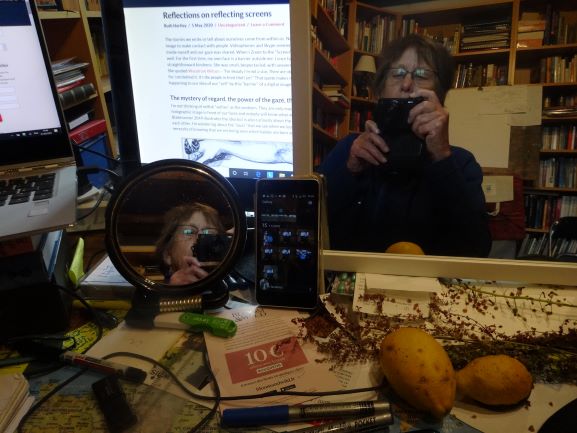 The photo shows mirrors, computer screens and a mobile phone with reflections of Ruth taking a self-portrait on her camera
