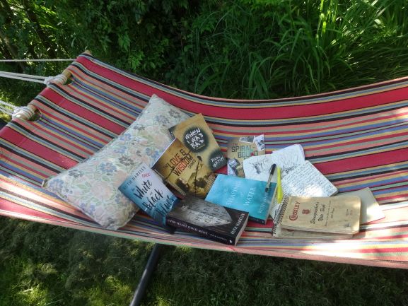 Image shows a striped hammock in which are all 5 of Ruth's published books with pens and notebooks.