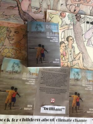 Photo of several copies of the book  "Dust and Rain" lying over some of Ruth Hartley's orginal artwork for the story.