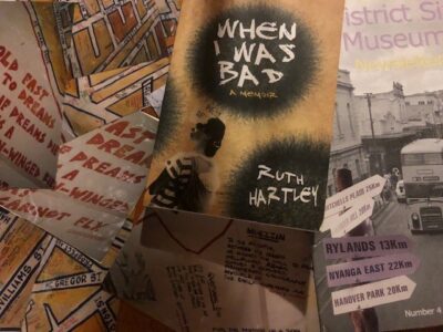Photo of the book "When I Was Bad" by Ruth Hartley lying over a map and a book about the District Six Museum in South Africa.