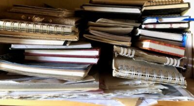 The photo shows  a bundle of notebooks and sketch books of all sizes and varieties.